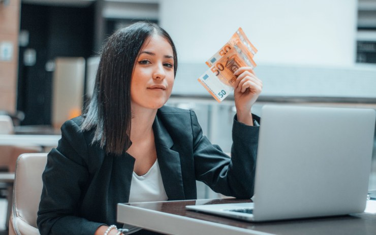 Ragazza al pc che mostra banconote euro