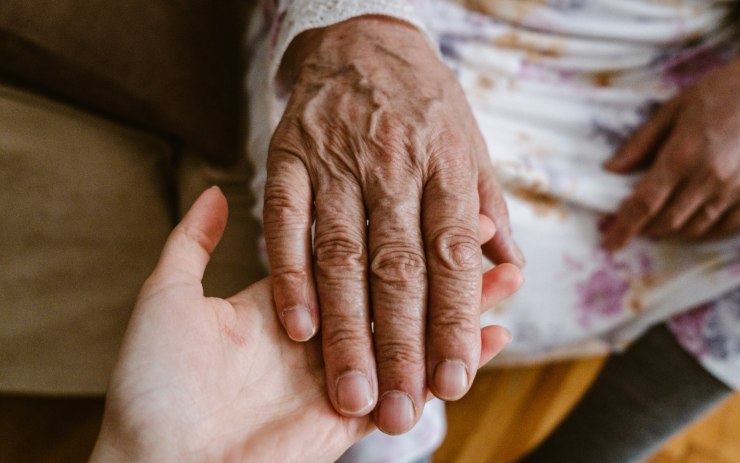 figlia che tiene la mano della madre anziana: supporto di un caregiver