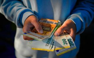 ragazzo che tiene in mano delle banconote euro