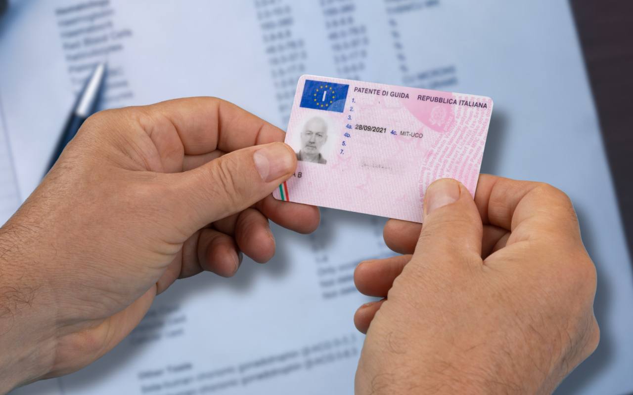 Uomo con in mano la sua patente e documentazione sullo sfondo