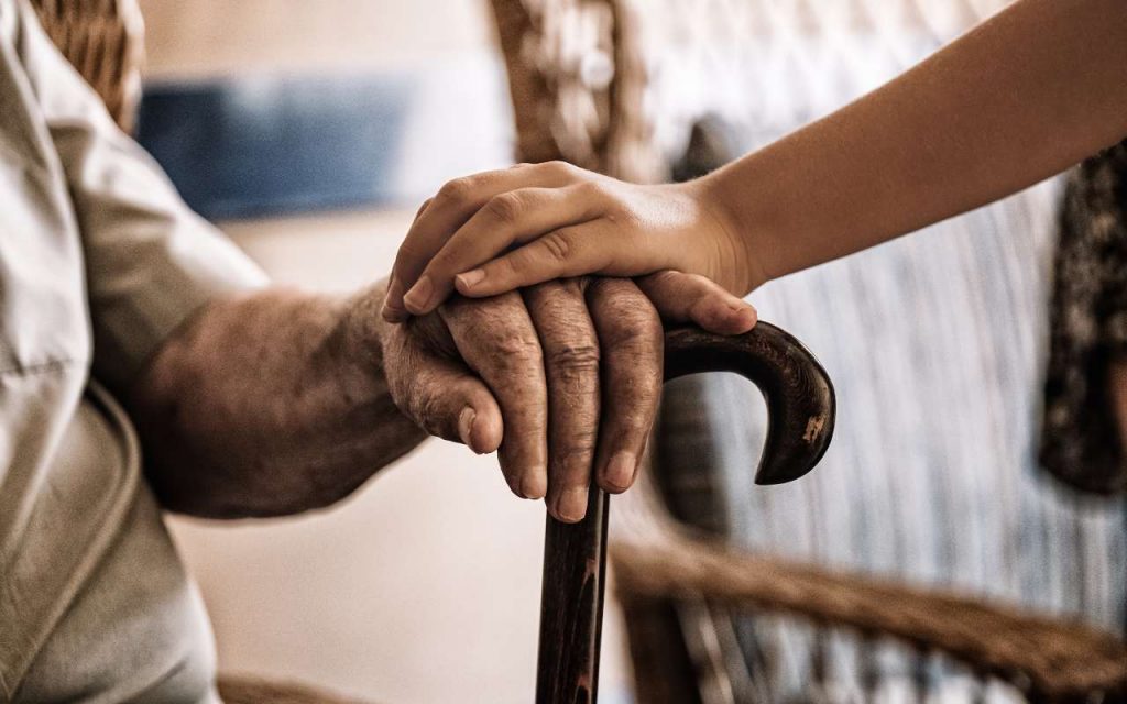 Nipote che tocca la mano di suo nonno con il bastone: cura e supporto